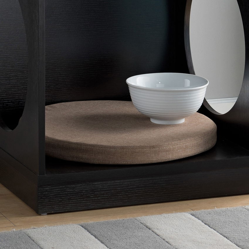 The Circle Design Comfortable Pet End Table With Removable Mat - Red Cocoa features a white ceramic bowl on a round cushion inside a black wood box with circular cutouts, placed beside a striped rug on a wooden floor.