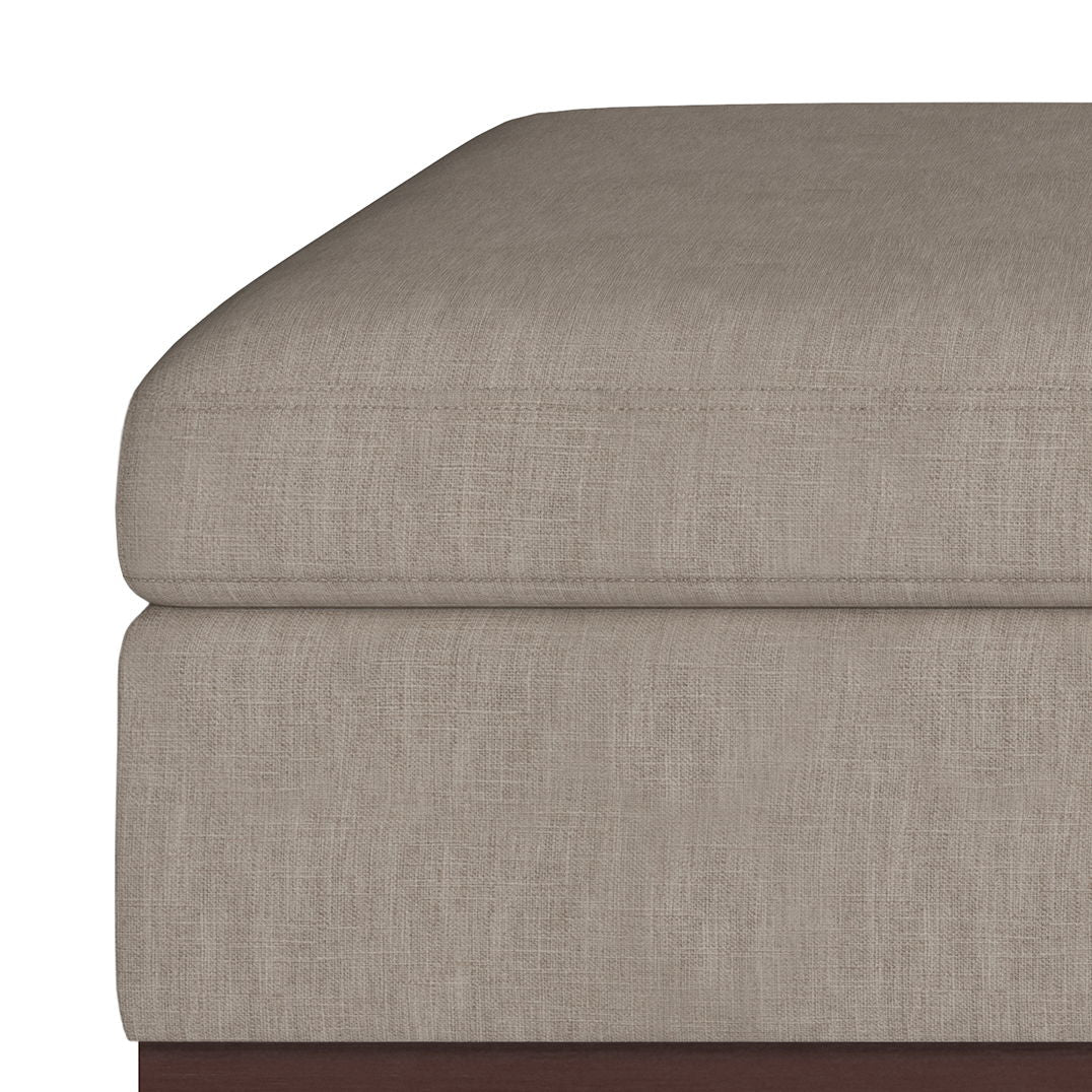 Close-up of the corner of the Owen Multifunctional Square Coffee Table Storage Ottoman, featuring beige upholstery with visible stitching on a wooden base.