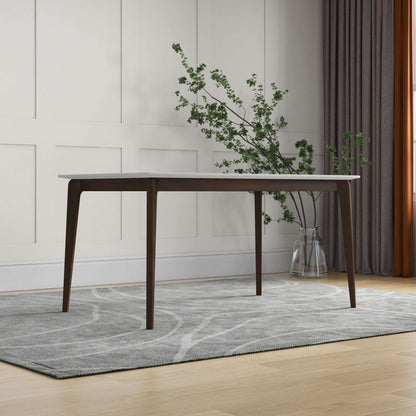 The Levi - Modern Style Rectangular Dining Kitchen Table with a white top stands on a gray patterned rug in a minimalist room with paneled walls, floor-length curtains, and a potted glass vase holding greenery.