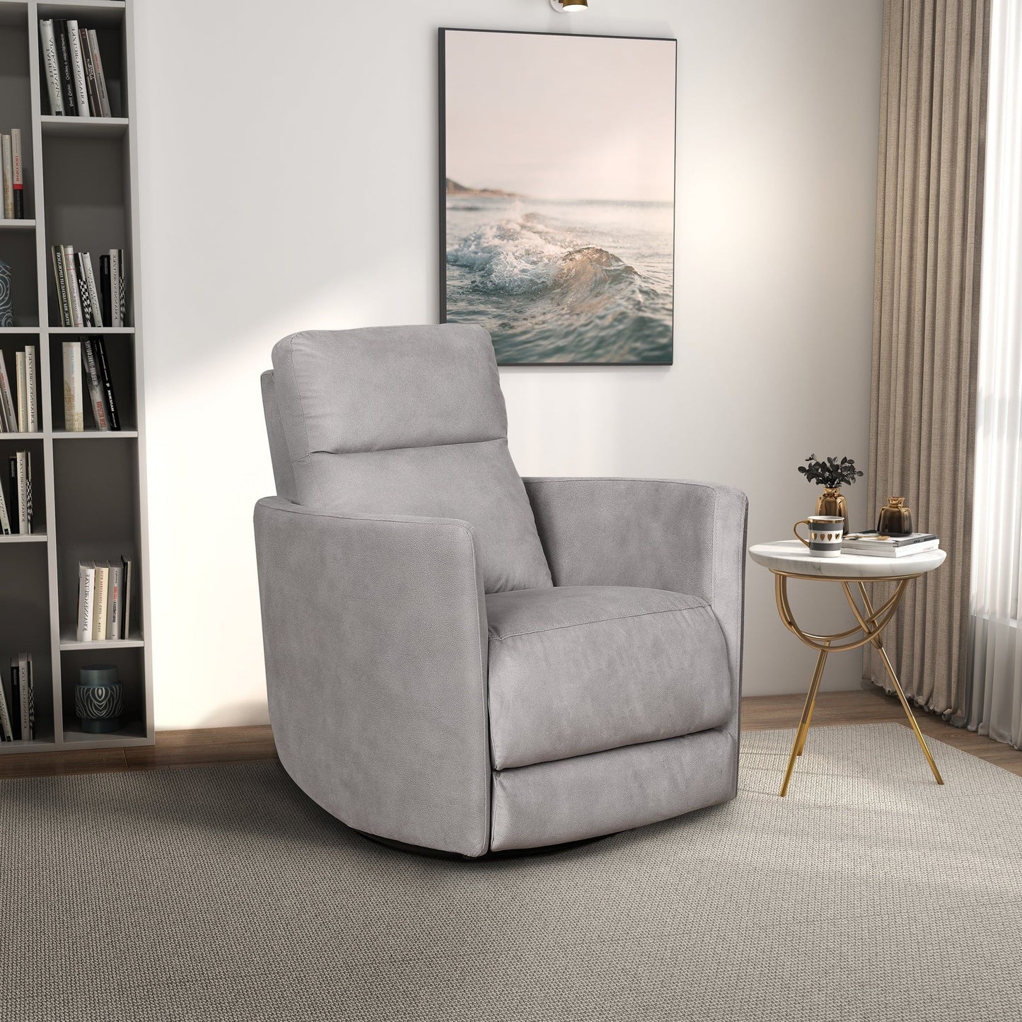 A modern living room features the Lawson Swivel Glider Suede Recliner Chair in Latte on a light carpet, a round white and gold side table with decor, a bookshelf, a large window with beige curtains, and seascape artwork on the wall.