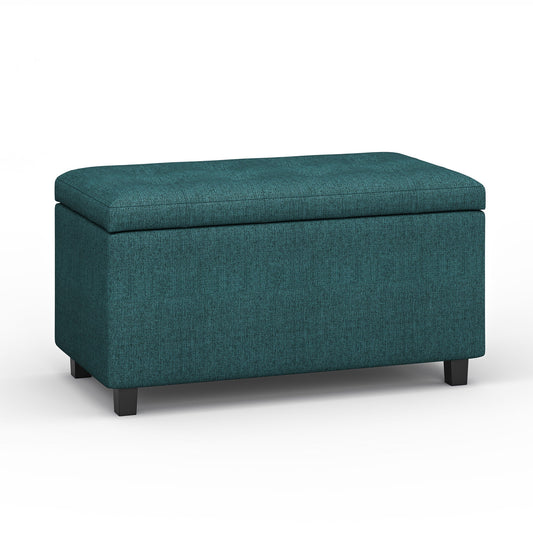 The Cosmopolitan Upholstered Storage Ottoman features a teal fabric, rectangular shape, cushioned lid, and short black legs, shown against a plain white background.