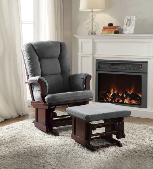 A cozy living room features the Adeliza Microfiber Glider Chair with Ottoman in gray on a plush rug, next to a lit fireplace with a white mantel, lamp, books, and decor. Sunlight filters through curtained windows.