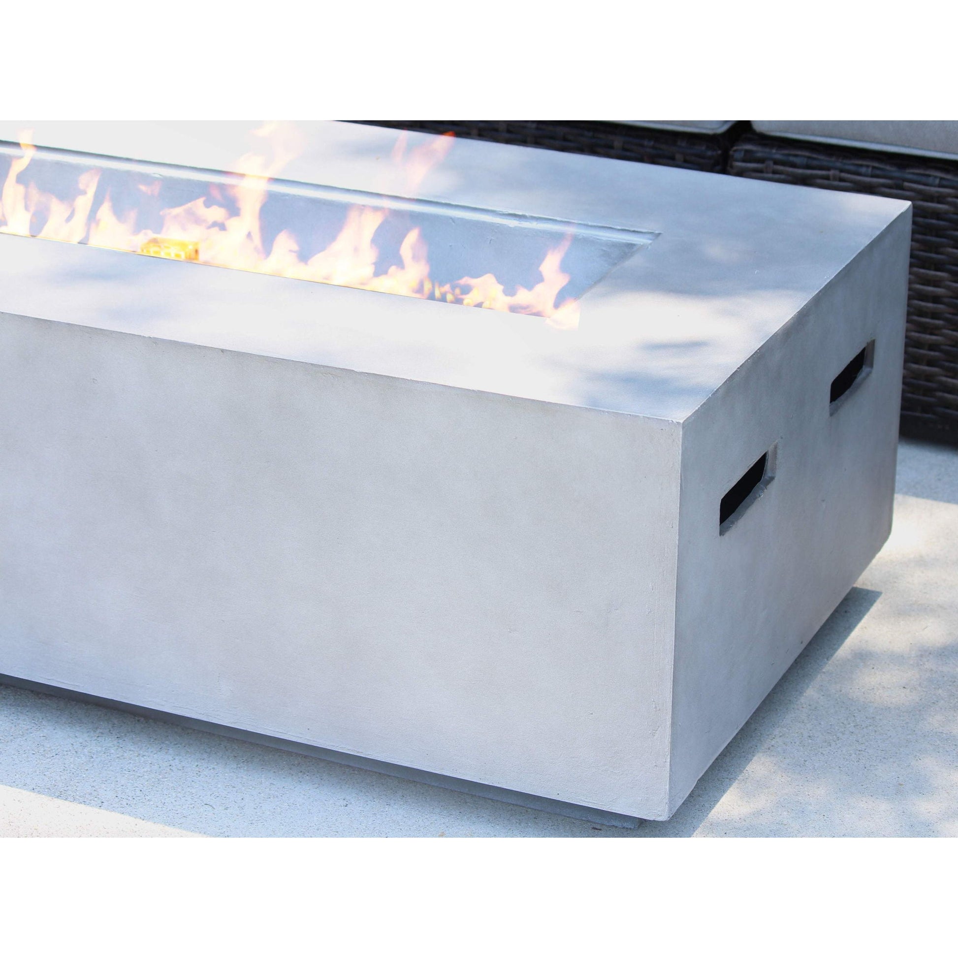 The Modern Concrete Design Propane Outdoor Fire Pit Table features a rectangular shape with visible center flames, ideal for adding style to a light-colored outdoor patio.