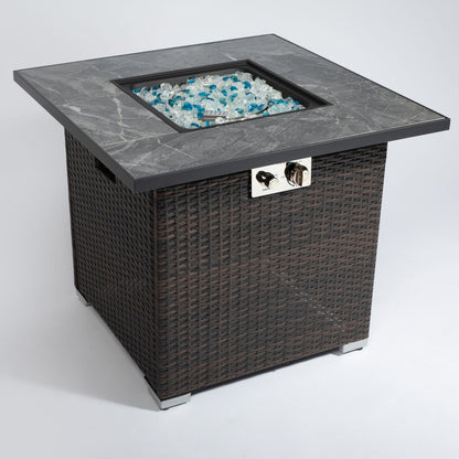 The 30" Espresso Outdoor Fire Table features a propane gas fire pit with lid, glass rocks in the center, rain cover, and a visible control panel on one side. It has a square design with a dark base and gray stone top.