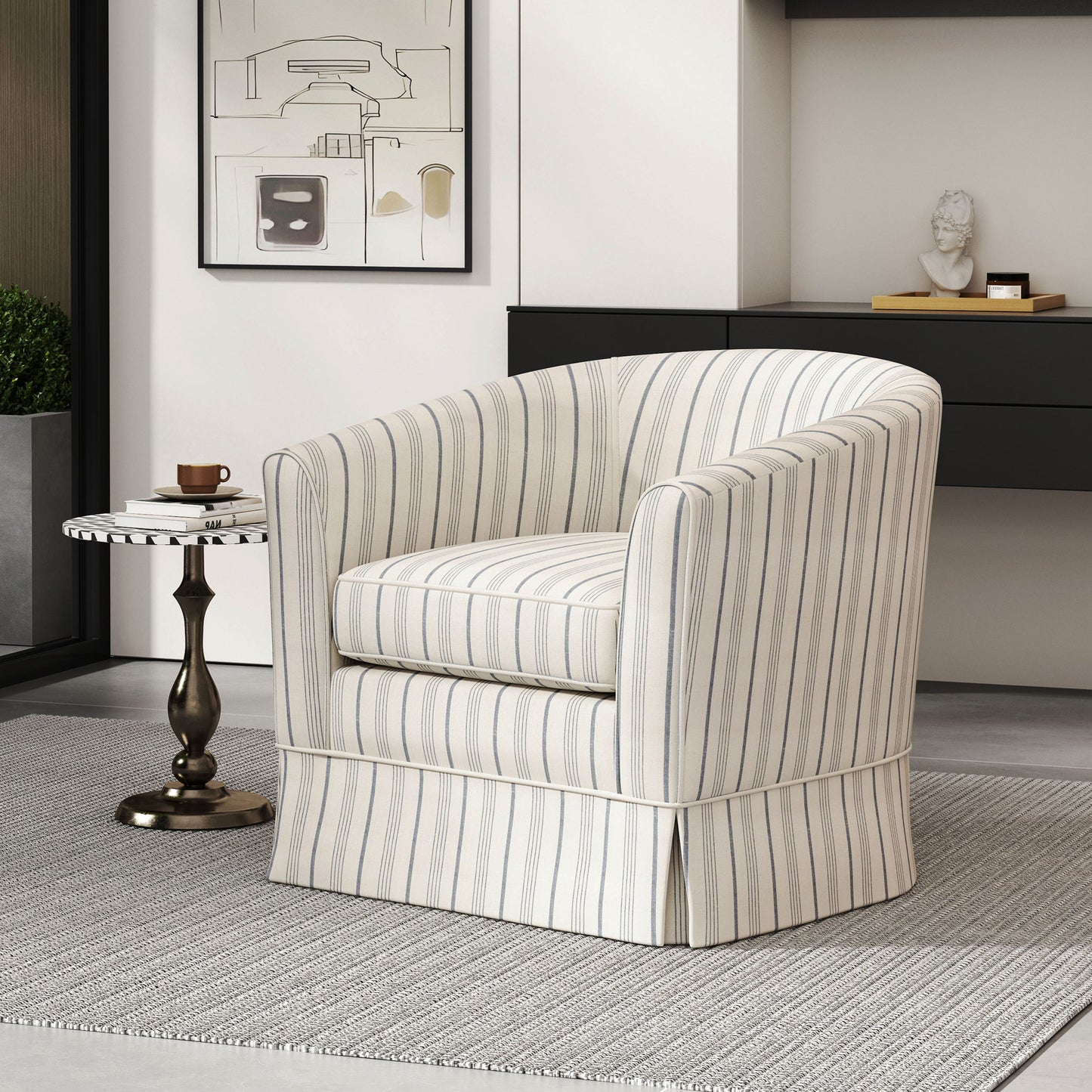 The Zeniqua Upholstered Velvet Swivel Chair with loose cover sits on a gray rug beside a small round side table holding a cup and saucer, with modern art and a decorative bust displayed in the background.