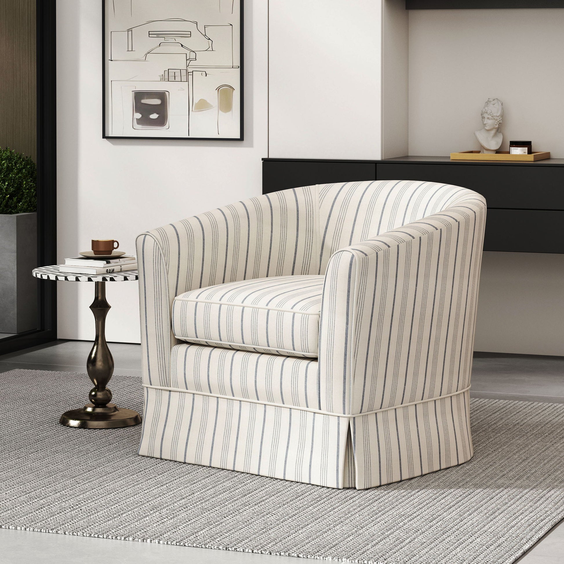 The Zeniqua Upholstered Velvet Swivel Chair with loose cover sits on a gray rug beside a small round side table holding a cup and saucer, with modern art and a decorative bust displayed in the background.