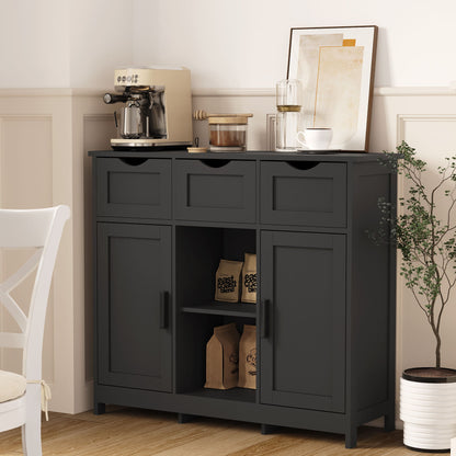 A sleek black wooden floor cabinet with drawers and shelves stores coffee supplies. On top sit a coffee machine, cups, a glass carafe, and framed art. A small potted tree stands next to the accent cabinet.