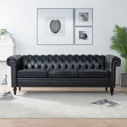 The Traditional Square Arm Removable Cushion 3 Seater Sofa in black leather, featuring rolled arms and silver studs, sits on a light rug in a modern living room with framed wall art, a green plant, and a magazine on the floor.