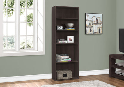 A 6-tier transitional bookcase stands by a window against a light green wall, holding books, decor, and a radio. Nearby are artworks and a TV.