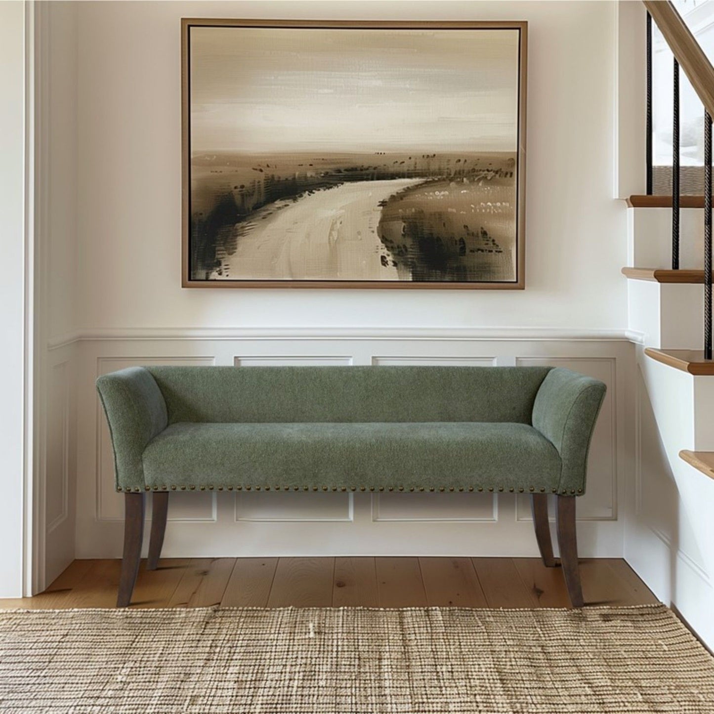 An Elegant Design Bench Upholstery with a solid wood frame, in green, sits against a white paneled wall below a large landscape painting. A woven rug covers the wooden floor near a staircase with a black handrail.