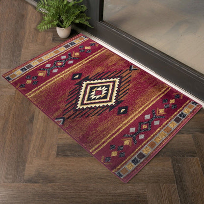 The Tribes - GC_YLS4002 Southwest Area Rug with red and gold geometric patterns lies on a wooden floor near a glass door, complemented by a nearby potted green plant.