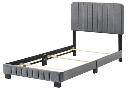 The Lodi - Bed is a modern single bed frame in gray fabric with a tall, vertically paneled upholstered headboard, matching footboard, sturdy wooden slats, and short legs. Shown without a mattress.