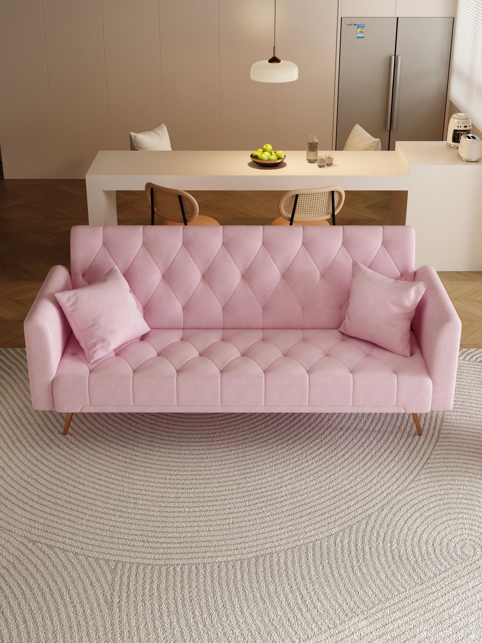 A modern living room features a pink Convertible Double Folding Living Room Sofa Bed with two matching pillows on a round textured rug. In the background are a dining table, chairs, bowl of green apples, pendant light, and refrigerator.
