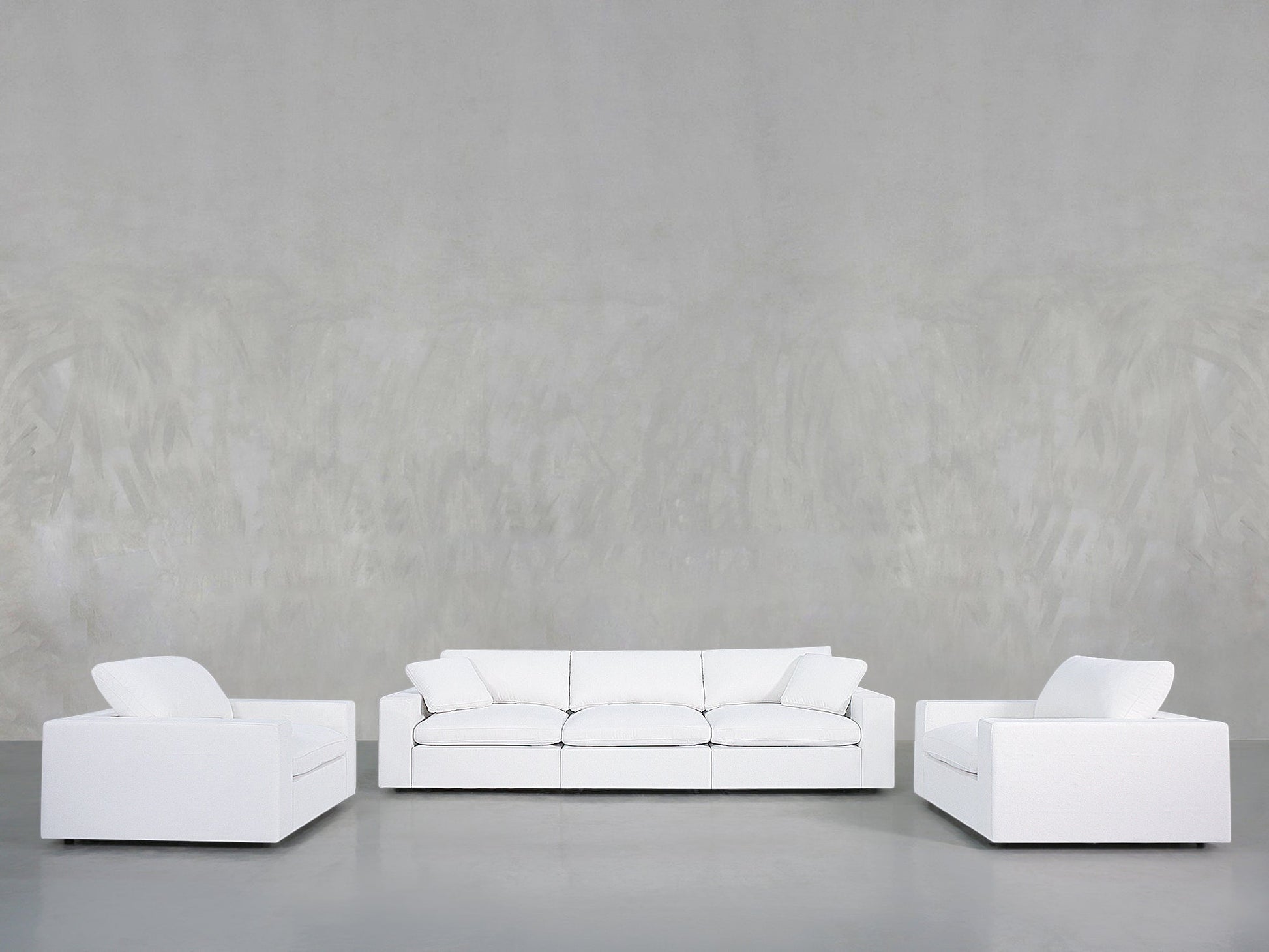 The 3-1-1 Sofa & Armchair Set is arranged in a U-shape in a minimalist room with a plain light gray wall and gray floor, creating a clean, uncluttered space that highlights simplicity and spaciousness.