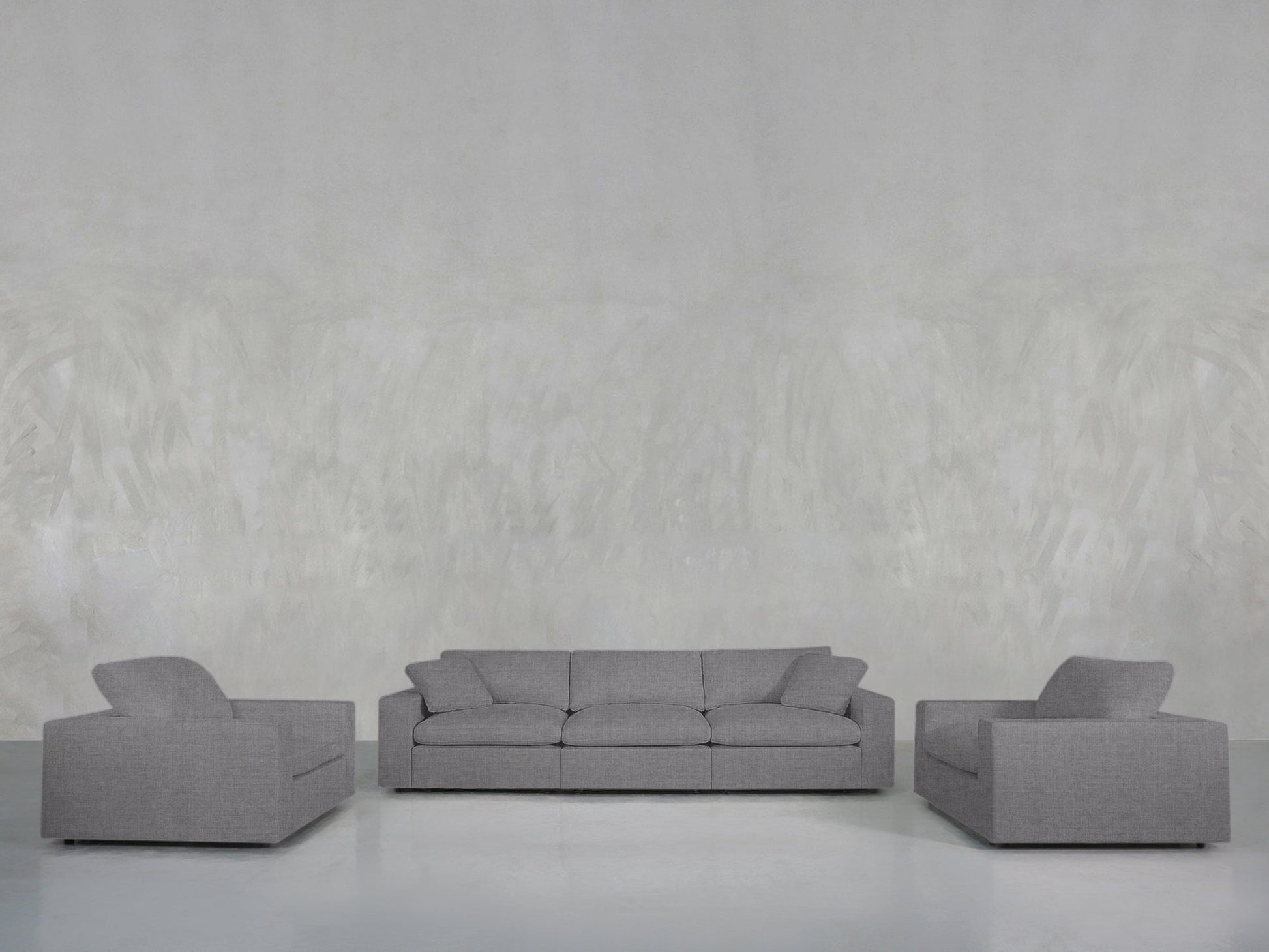 The 3-1-1 Sofa & Armchair Set features a gray sofa and two matching armchairs, arranged on a light floor against a textured light gray wall for a minimalist living room look.