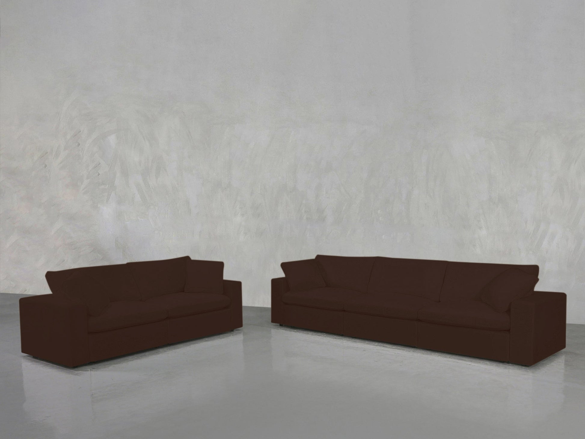 The 3-2 Sofa Set, featuring a dark brown two-seater and three-seater, is placed apart on a shiny light gray floor against a textured light gray wall.