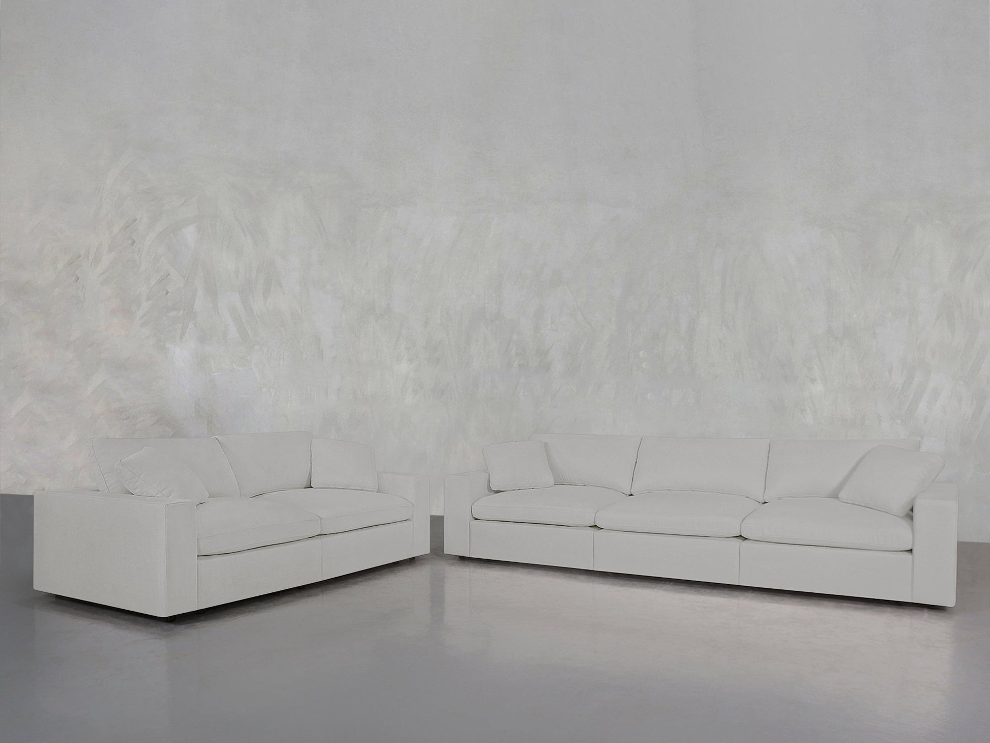 The 3-2 Sofa Set in modern white is arranged against a textured light gray wall on a smooth gray floor, creating a minimalist and spacious living room ambiance.
