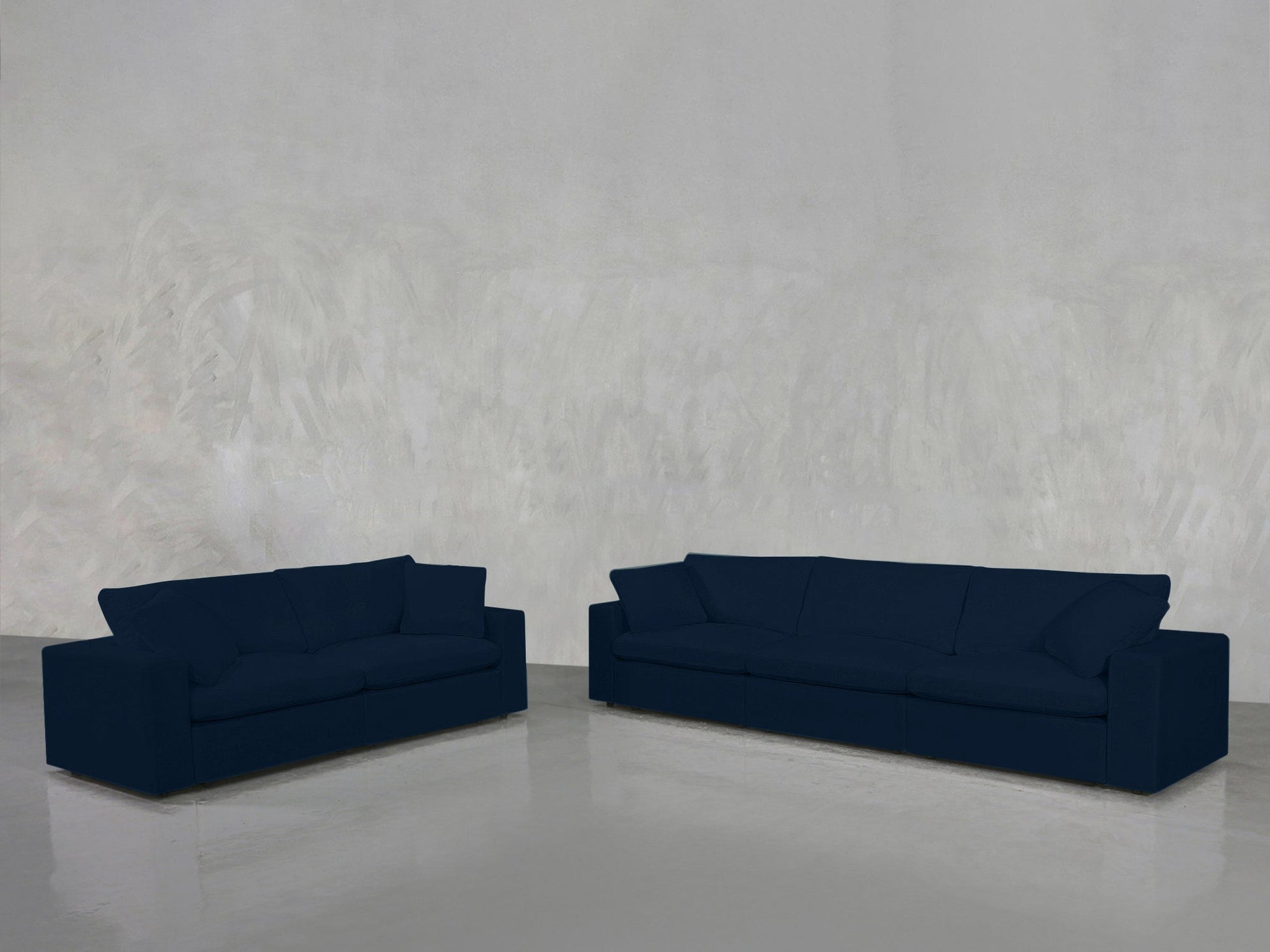 A 3-2 Sofa Set in dark blue is arranged in an empty room with a light gray textured wall and a glossy floor.
