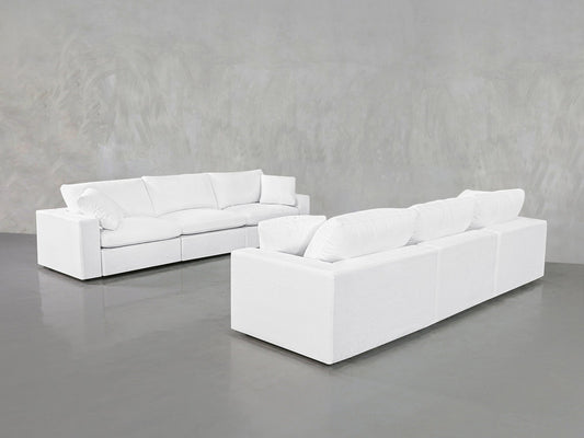 Two stylish 3-3 Sofa Sets with plush cushions stand on a shiny gray floor against a light gray textured wall, creating a minimalist atmosphere.