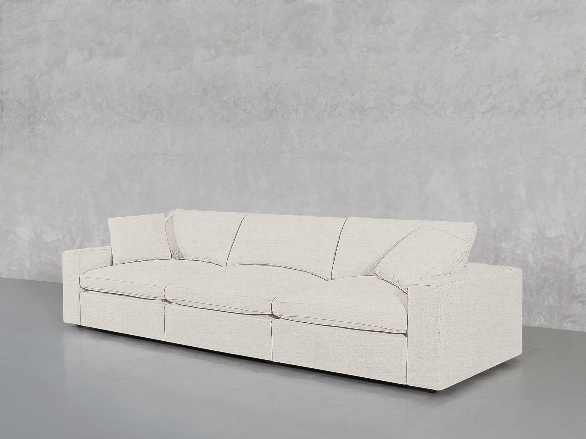 The 3-Seat Modular Sofa, featuring straight arms and plush cushions in white, is placed on a smooth gray floor against a textured light gray wall.