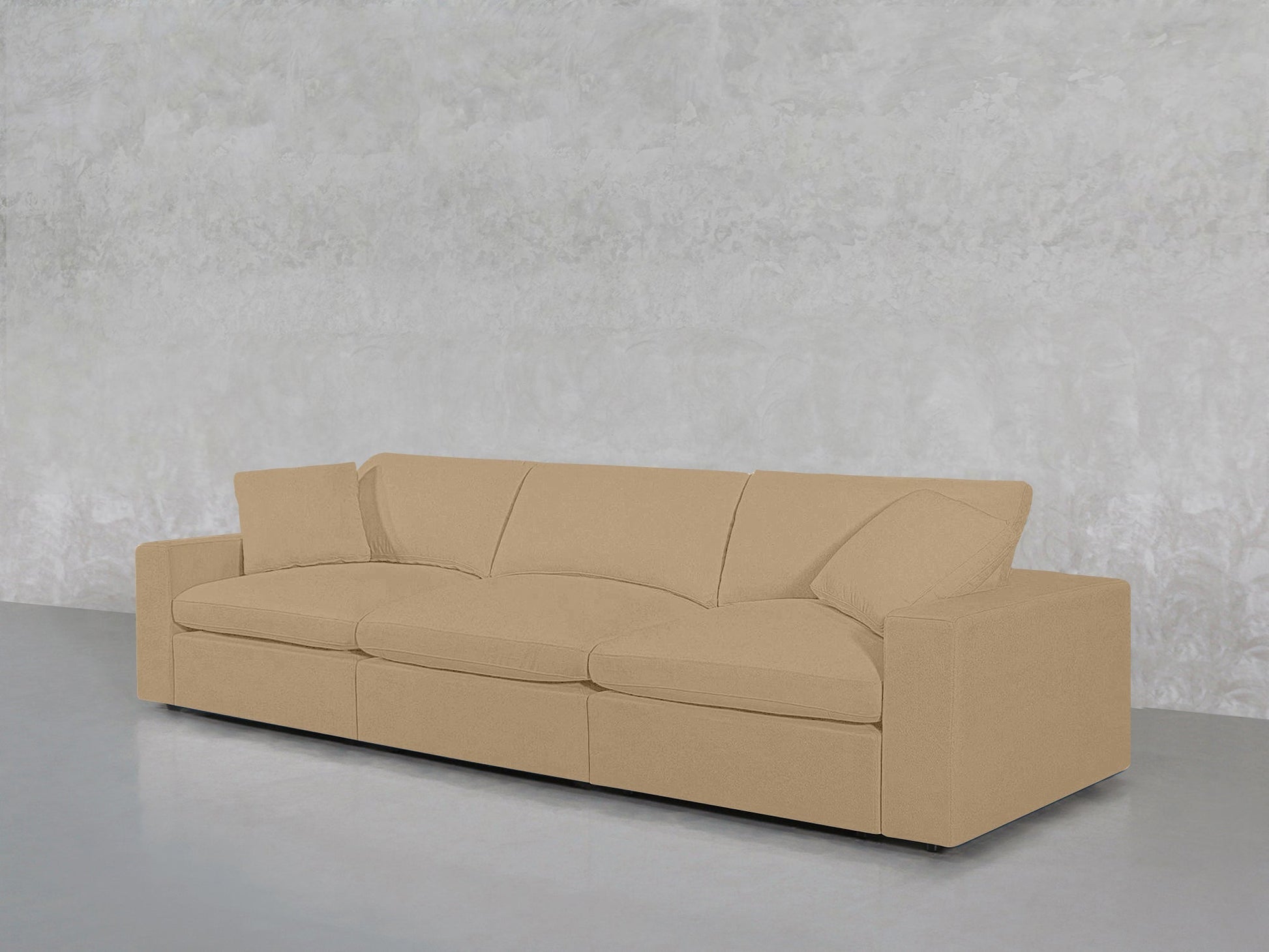 The 3-Seat Modular Sofa, in beige with straight arms and three seat cushions, is placed against a light gray textured wall on a smooth gray floor.