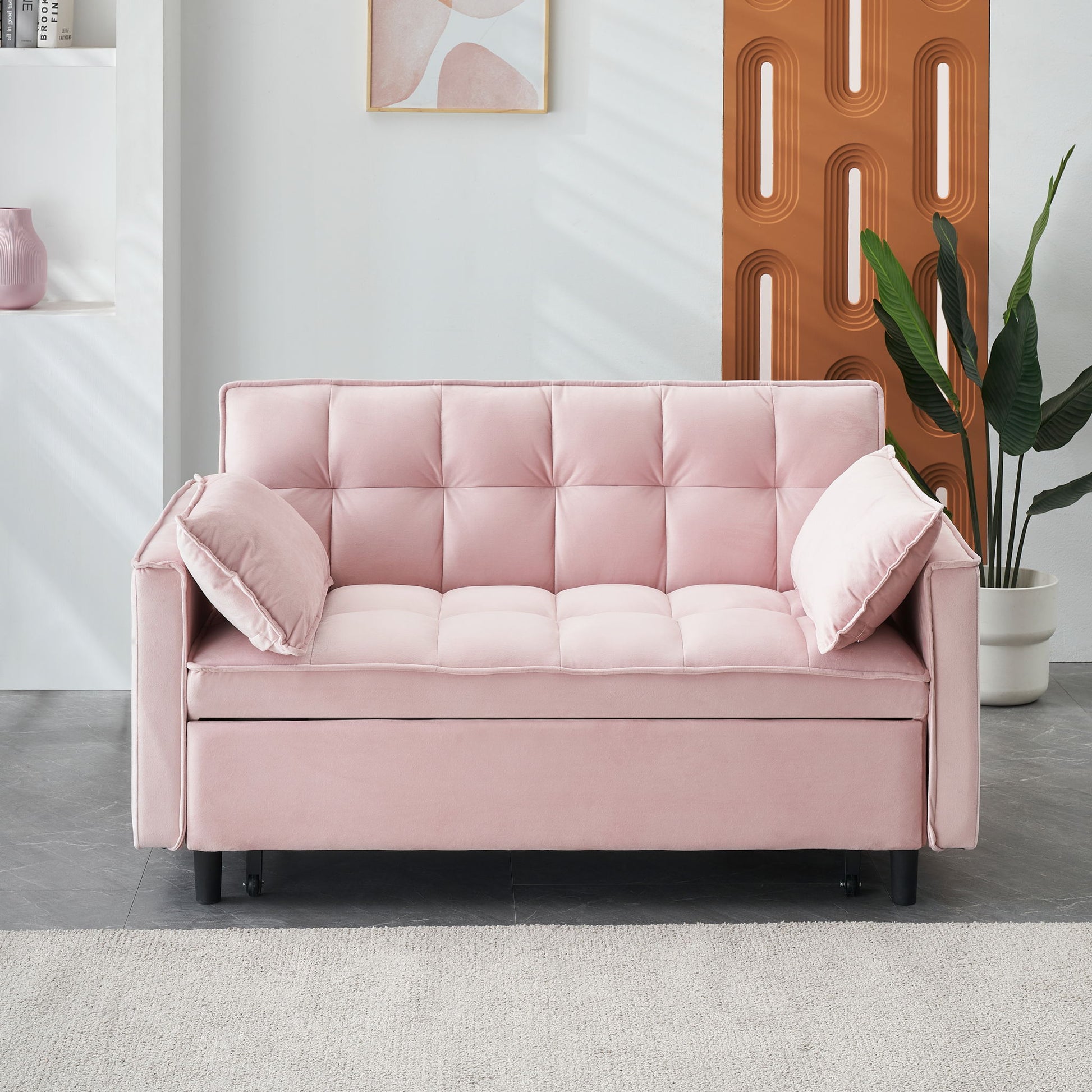 A modern living room featuring the Modern Velvet Sofa 3-in-1 Convertible Sleep Sofa Bed with two side pillows, a potted green plant, abstract wall art, and contemporary decor in soft neutral tones.