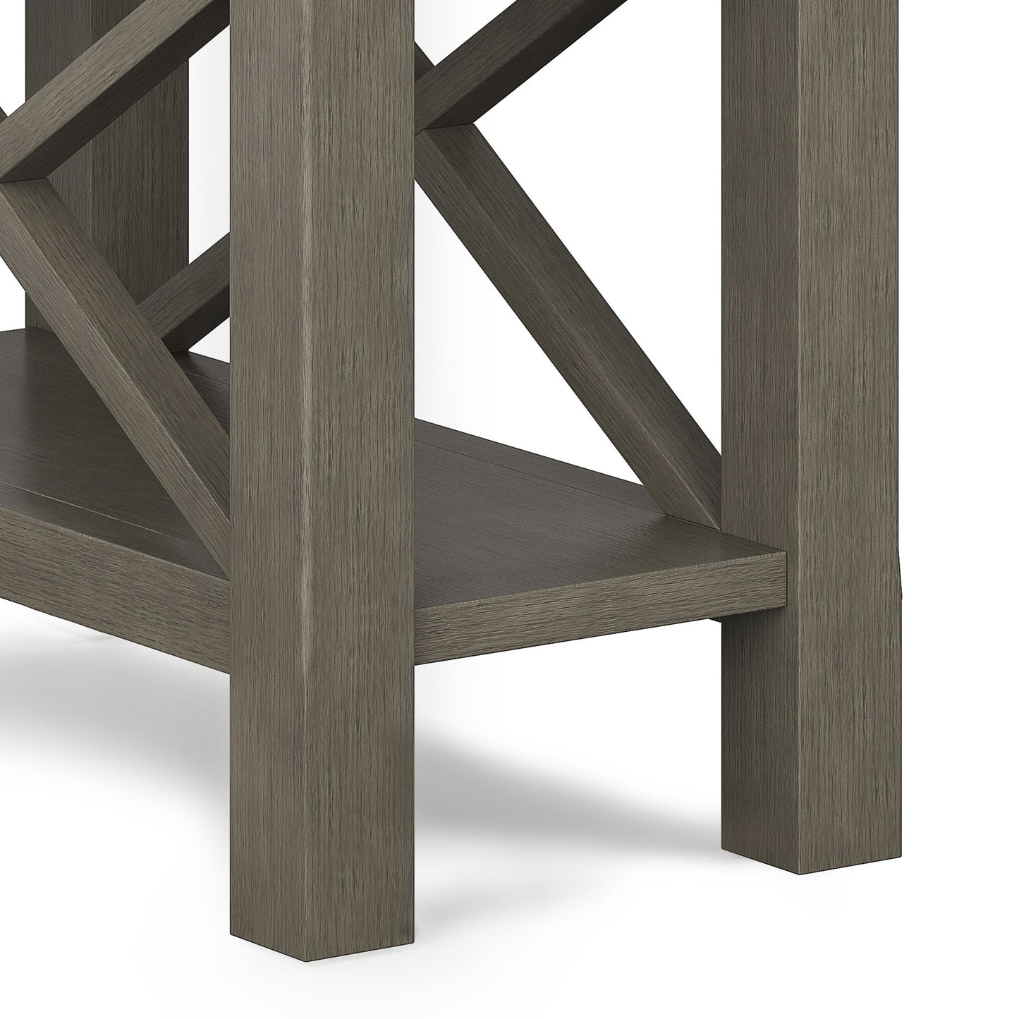 Close-up of the Kitchener - Handcrafted Table’s corner and legs with a grayish-brown finish, lower shelf, and crisscross support beams in the background.