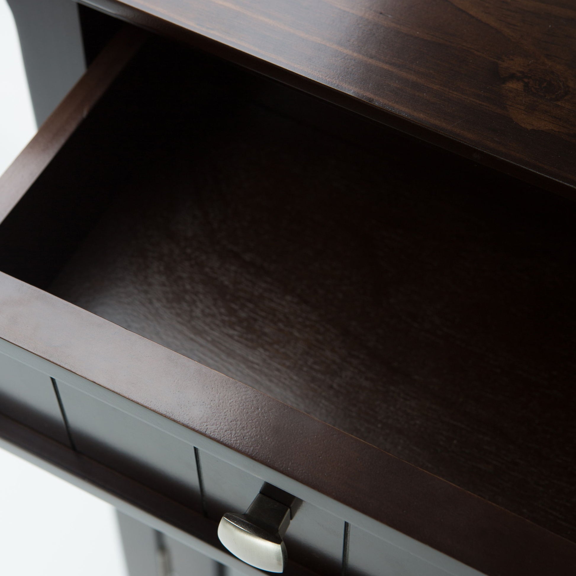Close-up view of an open, empty Acadian Entryway Storage Cabinet in Brunette Brown with a silver handle, showing its dark interior and part of the top surface.