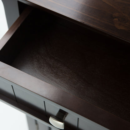 Close-up view of an open, empty Acadian Entryway Storage Cabinet in Brunette Brown with a silver handle, showing its dark interior and part of the top surface.
