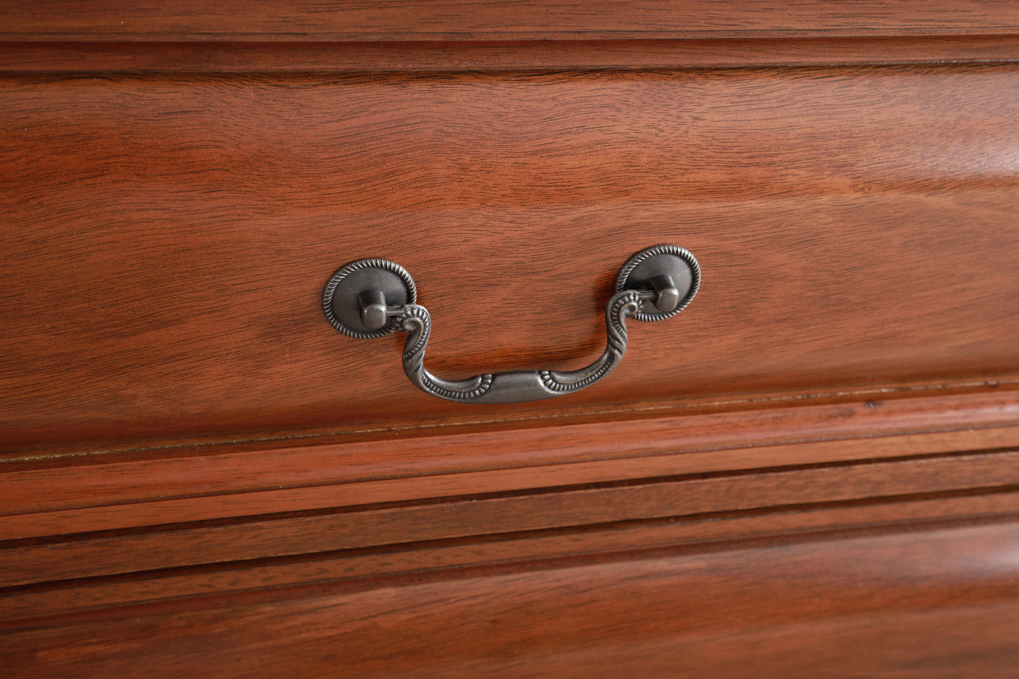 Close-up of the LaVita - Dresser's wooden drawer front with a smooth, polished finish and an ornate decorative metal handle featuring two round metal bases.