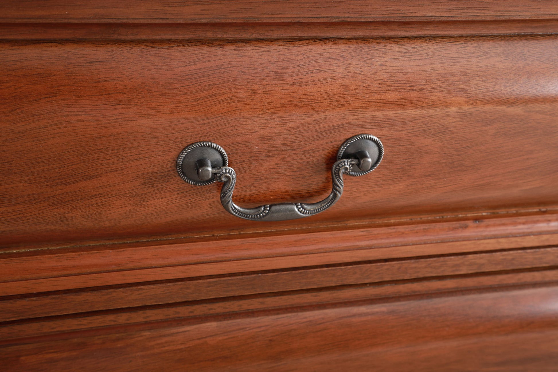 Close-up of the LaVita - Dresser's wooden drawer front with a smooth, polished finish and an ornate decorative metal handle featuring two round metal bases.