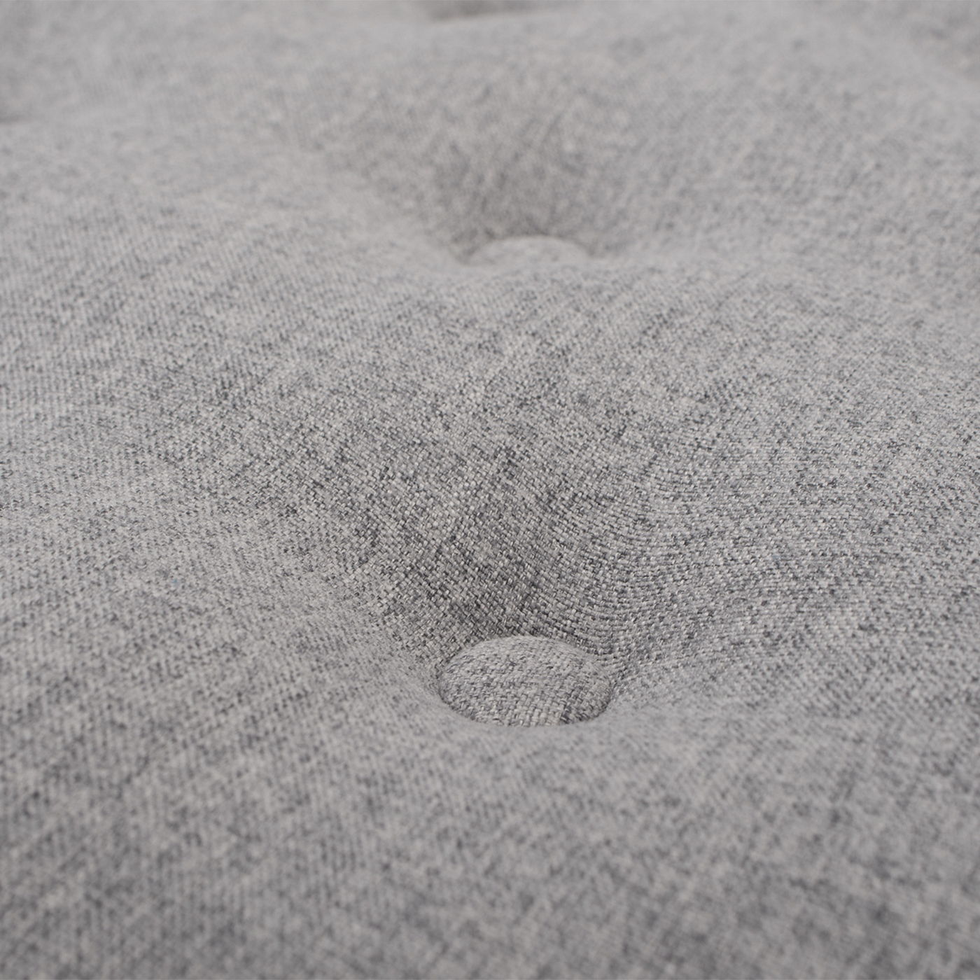 Close-up of the Yolanda Round Upholstered Accent Ottoman in light gray fabric, showcasing its soft texture and a centered, indented button tuft detail.