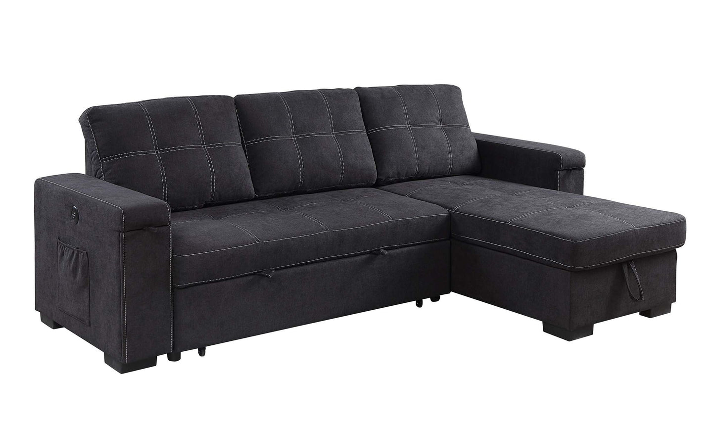 The Toby Woven Fabric Reversible Sleeper Sectional features dark gray upholstery, wide armrests, three back cushions, a right-side storage chaise, white stitching, a left arm pocket, cup holder, and built-in charging ports.