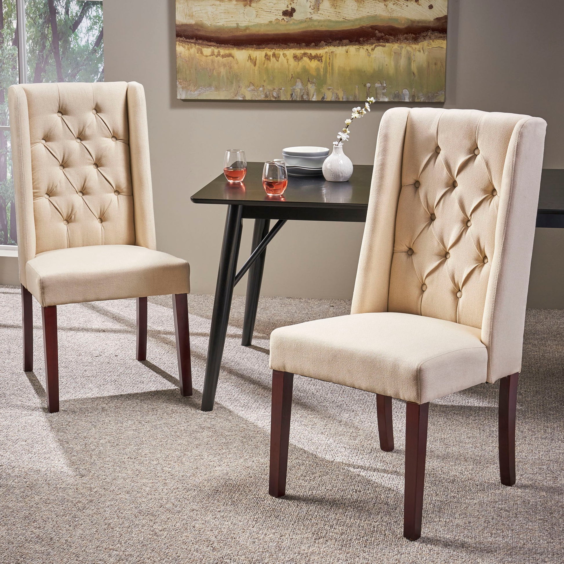Two Sophisticated Tufted Dining Chairs With High Back Design in beige sit on a carpet near a dark rectangular dining table, set with two glasses of rosé, a white flower vase, and plates, creating a modern dining room ambiance.