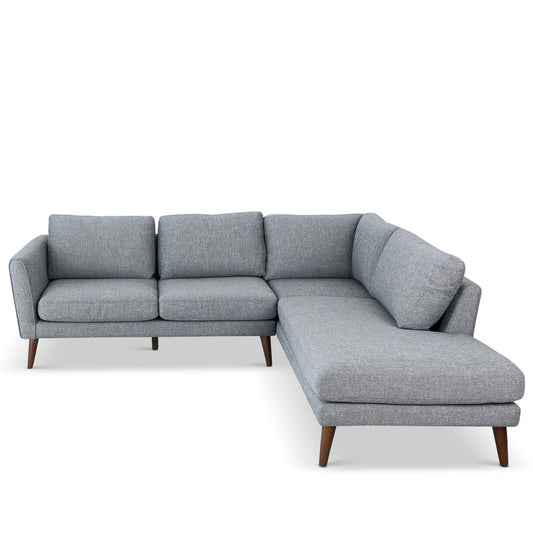 The Benson - Sectional Sofa With Chaise is a modern L-shaped grey fabric sofa with three left seat cushions, a right-side chaise lounge, wooden tapered legs, and clean lines.