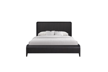 The Waterfall Panel Bed features a dark wooden frame and a vertical slat headboard, styled with crisp white bedding and two white pillows, set against a plain white background.