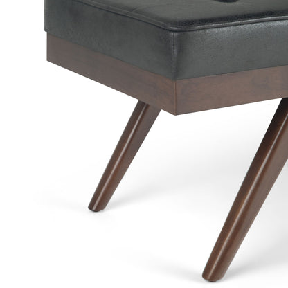 Close-up of the Pierce - Mid Century Upholstered Ottoman Bench featuring angled wooden legs with a rich brown finish and a tightly fitted dark upholstered cushioned seat.