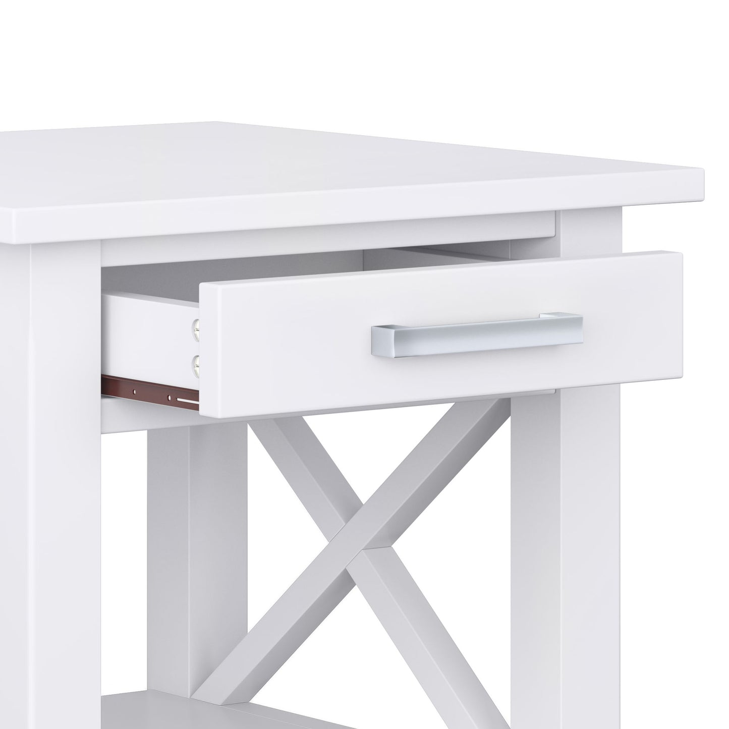 A close-up of the Kitchener - Handcrafted Table, featuring a white finish, open drawer with a silver handle, X-shaped side crossbars for support, a flat tabletop, and an open lower shelf for extra storage.