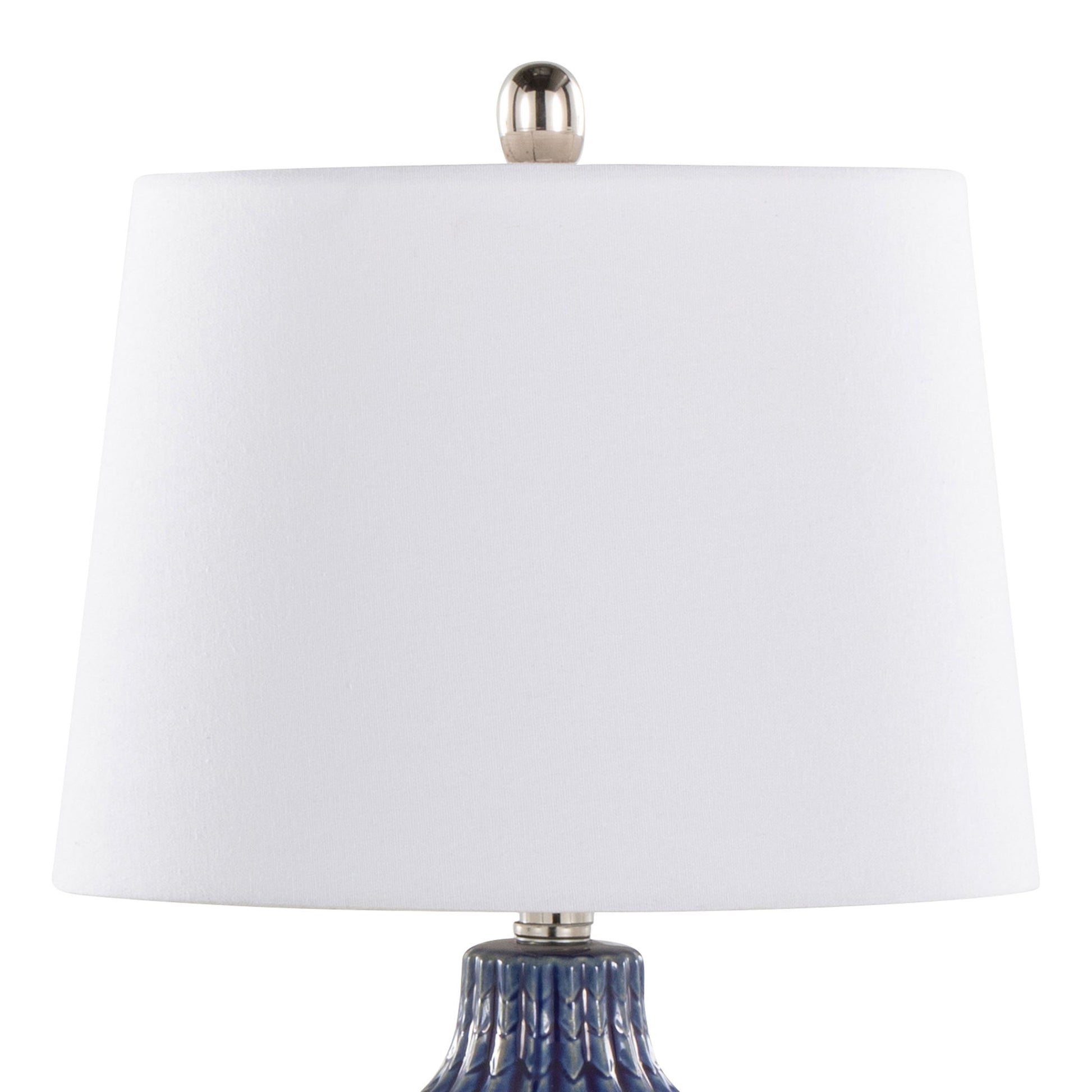 A close-up of the Rockwell - Contemporary Table Lamp (Set of 2), featuring a white cylindrical lampshade with a silver finial and a textured blue base partially visible.
