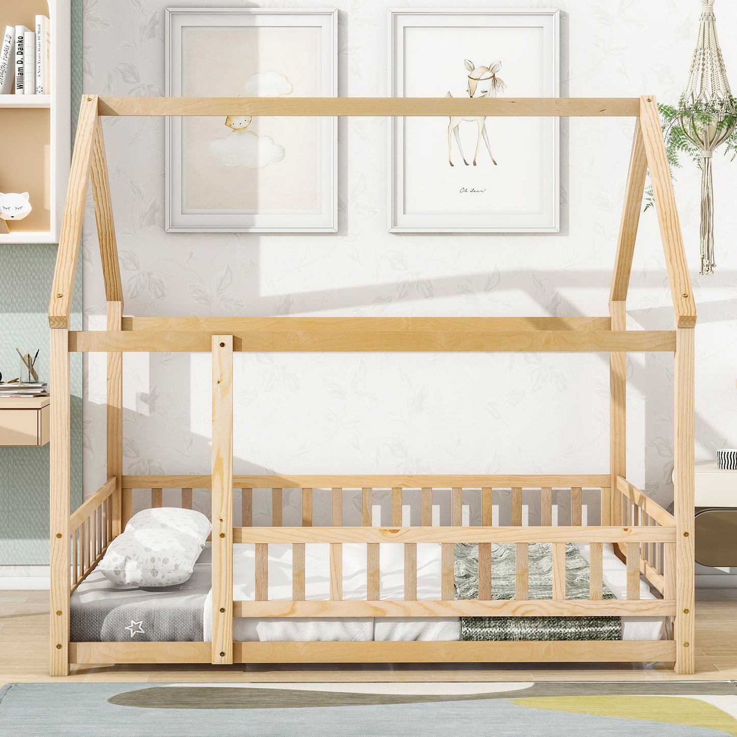 The Floor Wooden Bed With House Roof Frame and Fence Guardrails stands in a bright room with a low mattress, pillows, and blanket. Two animal prints hang above the bed, surrounded by playful children’s decor.