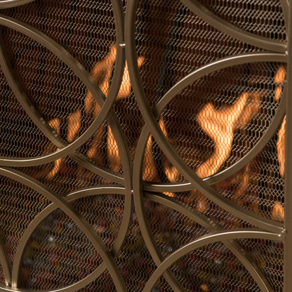Close-up of the Thayer Single Panel Iron Fireplace Screen featuring a geometric mesh design, positioned in front of a fireplace with visible orange flames in the background.