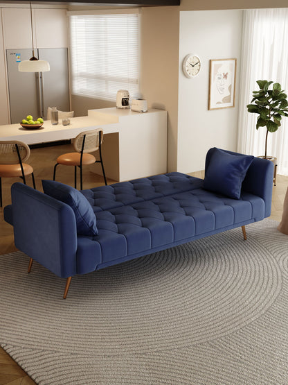 A modern living room features a Convertible Double Folding Living Room Sofa Bed with two matching pillows on a round gray rug, set against a backdrop of a kitchen and dining area filled with natural light.