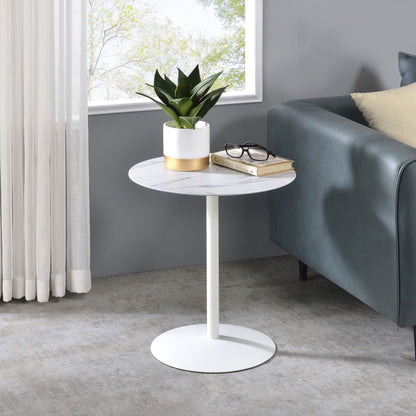The Circa 17.5" End Table With Marble Textured Top holds a potted plant, eyeglasses, and a closed book beside a dark green sofa near a window with sheer curtains.