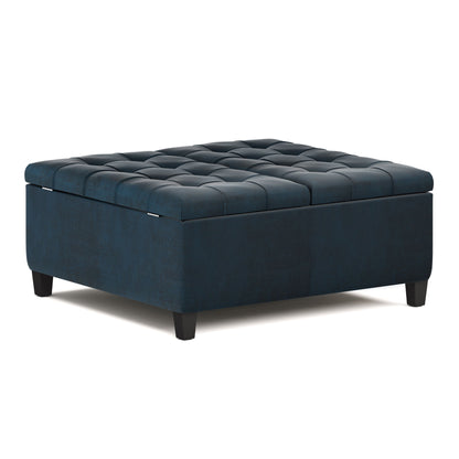 The Harrison Large Coffee Table Storage Ottoman features a square design, dark blue upholstery, a tufted top, short black legs, and a spacious storage compartment.