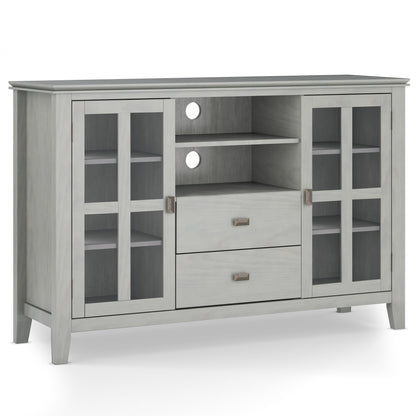 The Artisan Handcrafted Tall TV Media Stand features a light gray wooden finish, two glass-paneled cabinet doors on each side, two center drawers, two open shelves above, and circular cable cutouts on the back panel.