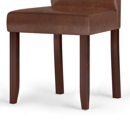 A close-up of the Acadian - Upholstered Parson Dining Chair (Set of 2) featuring a padded leather seat and backrest with four wooden legs, set against a white background.