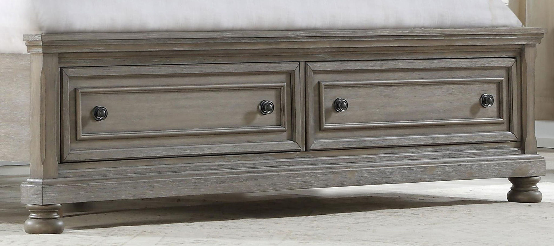 The Elegant Design Storage Bed features two front drawers, paneled detailing, round metal knobs, and turned legs, shown placed at the foot of a bed on a light-colored carpet.