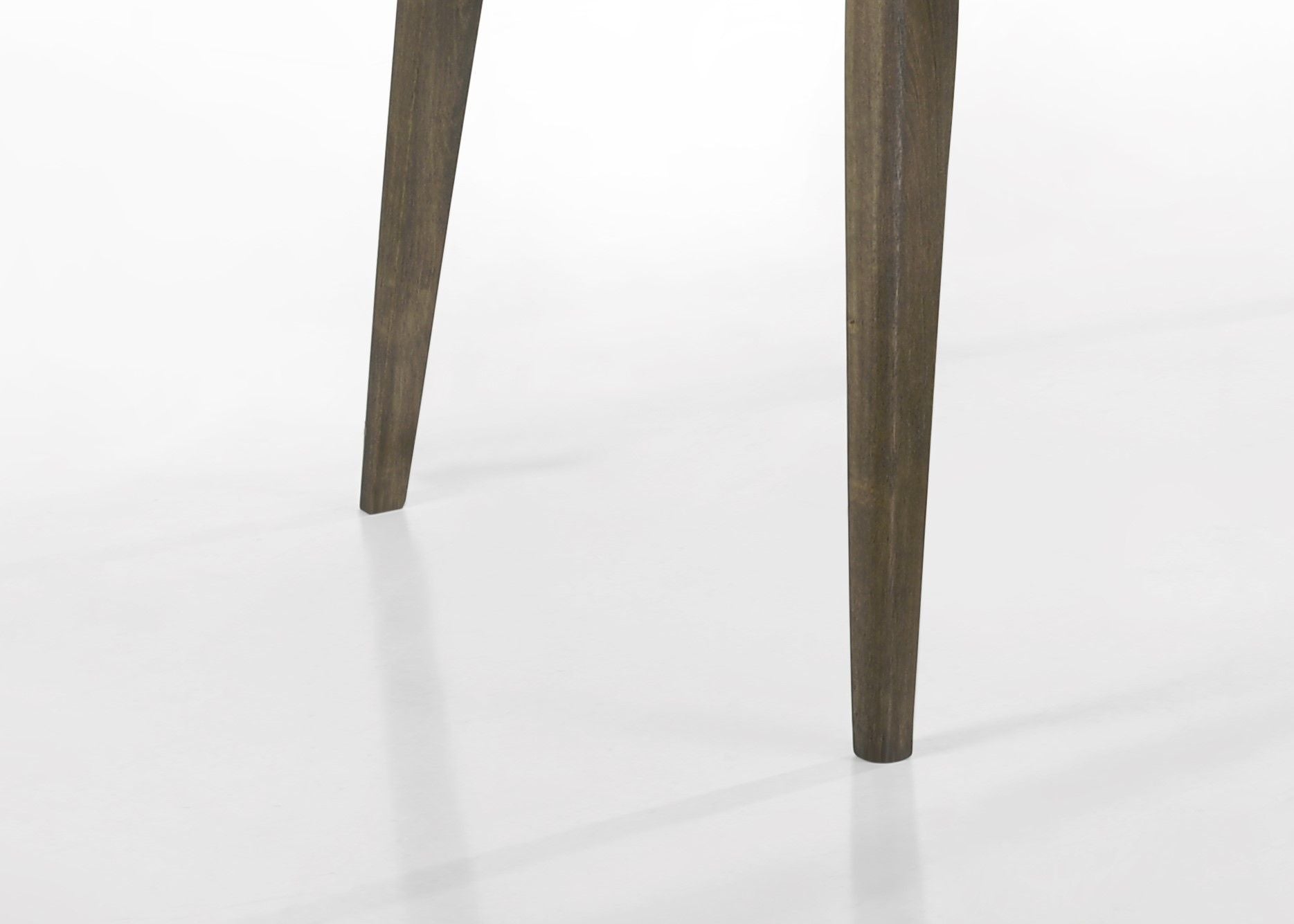 Two angled wooden legs with a dark finish from the Bistro Wide Contemporary Rectangle Dining Table With Extension Leaf stand on a white surface, casting faint shadows. The rest of the table is not visible.
