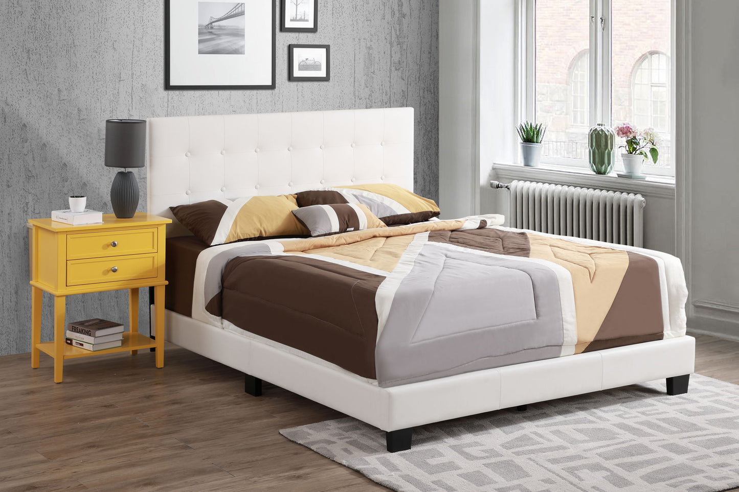 Modern bedroom featuring the Caldwell bed in white upholstery, geometric brown and beige bedding, a yellow nightstand with drawers, and decor accents by a large sunlit window.