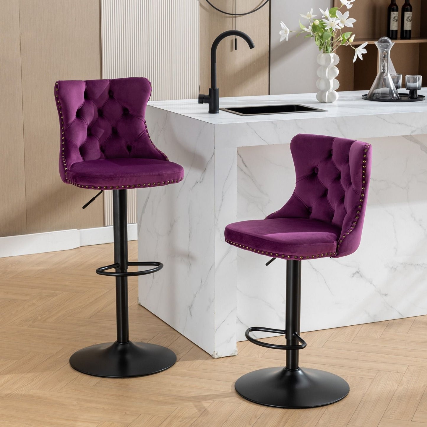Two Swivel Velvet Barstools with tufted backs and adjustable seat height are placed by a white marble kitchen island with a black faucet and vase of flowers. The kitchen features light wood floors and neutral walls.